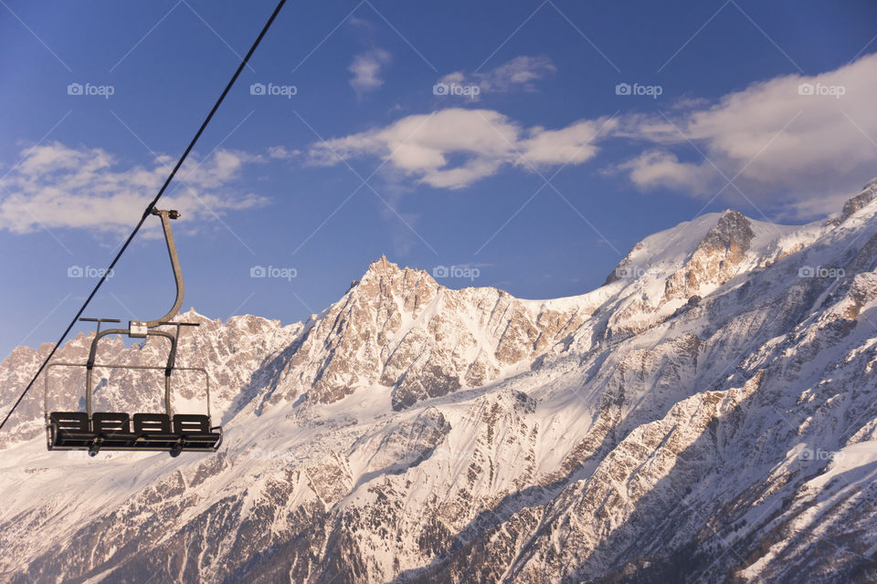 Four chair lifts on the Alps background.