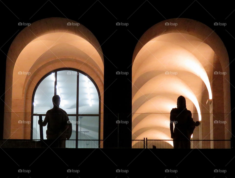 silhouette statues under a series of arches