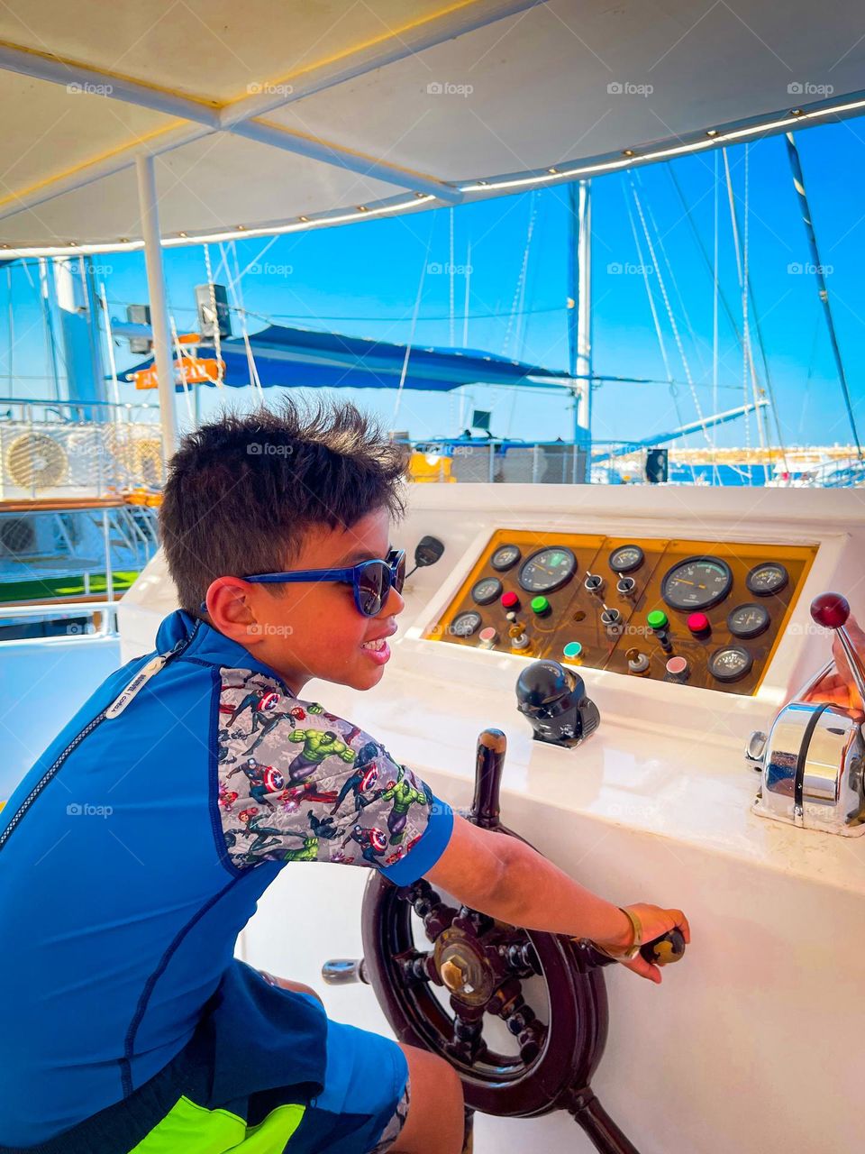 A 6 year old boy at the helm of a yacht. 