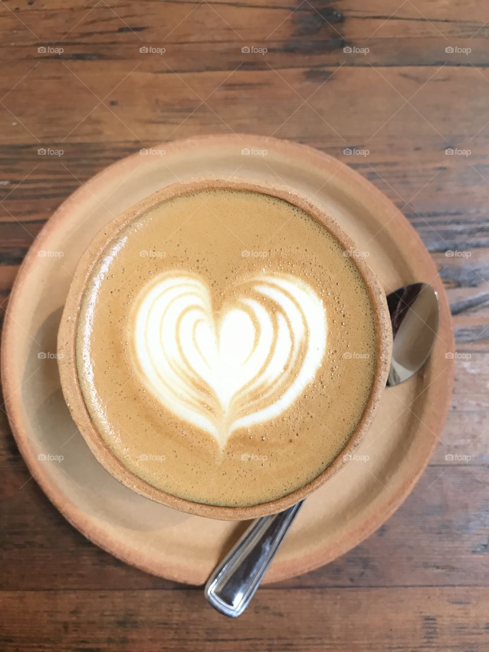 Overhead view of a mug of cappuccino with a foam heart on it.