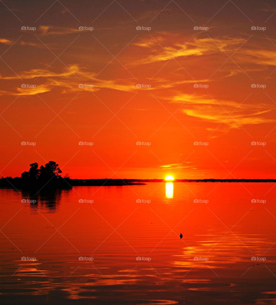 The big orange and crimson ball slowly going down and down and it sets into the horizon making the sky absolutely stunning