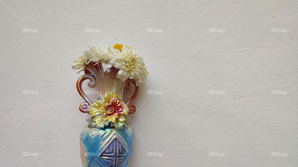 Beautiful white flowers in a colourful flowerpot with a flower sculpture, Flowers in a vase, colourful vase, white flowers in a vase