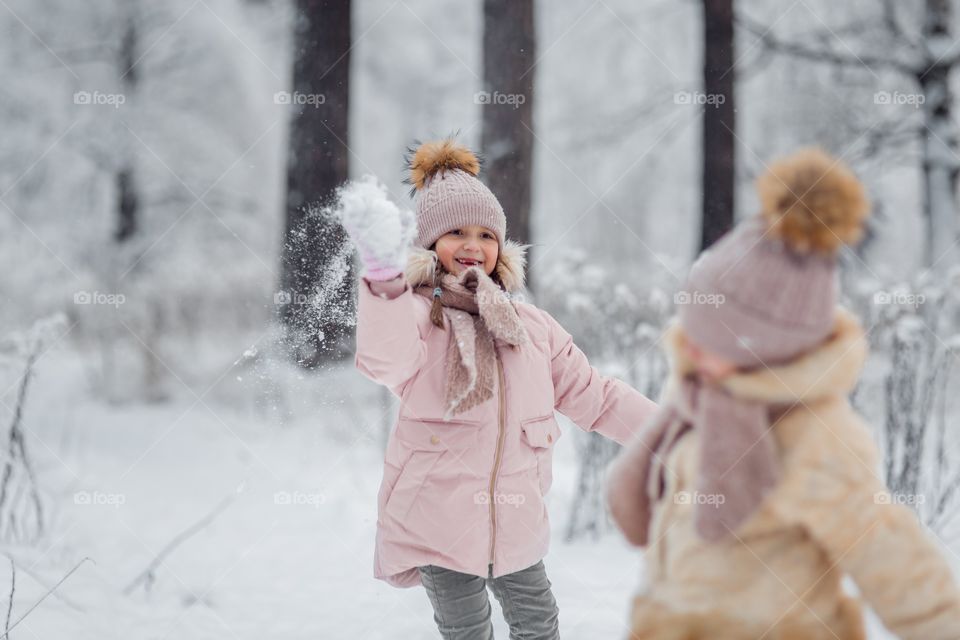 Little sisters playing outside with snow 