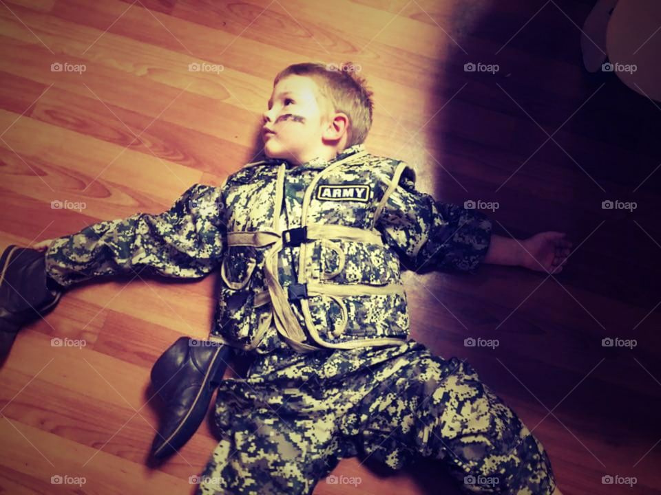 Little Army man, sprawled across beautiful wood floor with leather boots laying beside him.