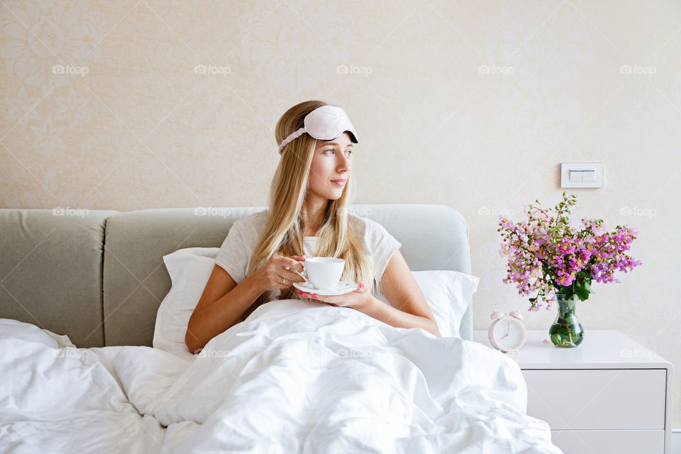 Young woman drinking coffee in the bed early morning 