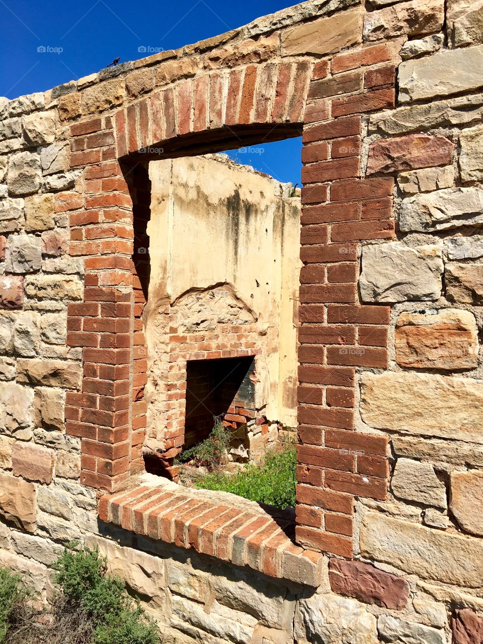 Old brick and stone colonial settlers house in south Australia, almost reduced to rubble, but you can see through the portal window the old stone fireplace. 