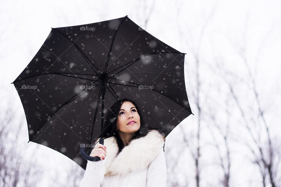 woman under umbrella while snowing