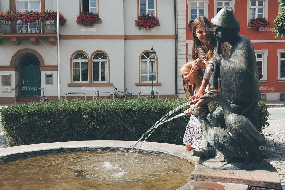 Little sisters near water fountain in park