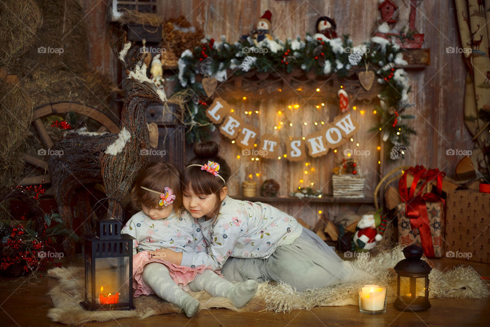 Little sisters near fireplace at Christmas Eve 