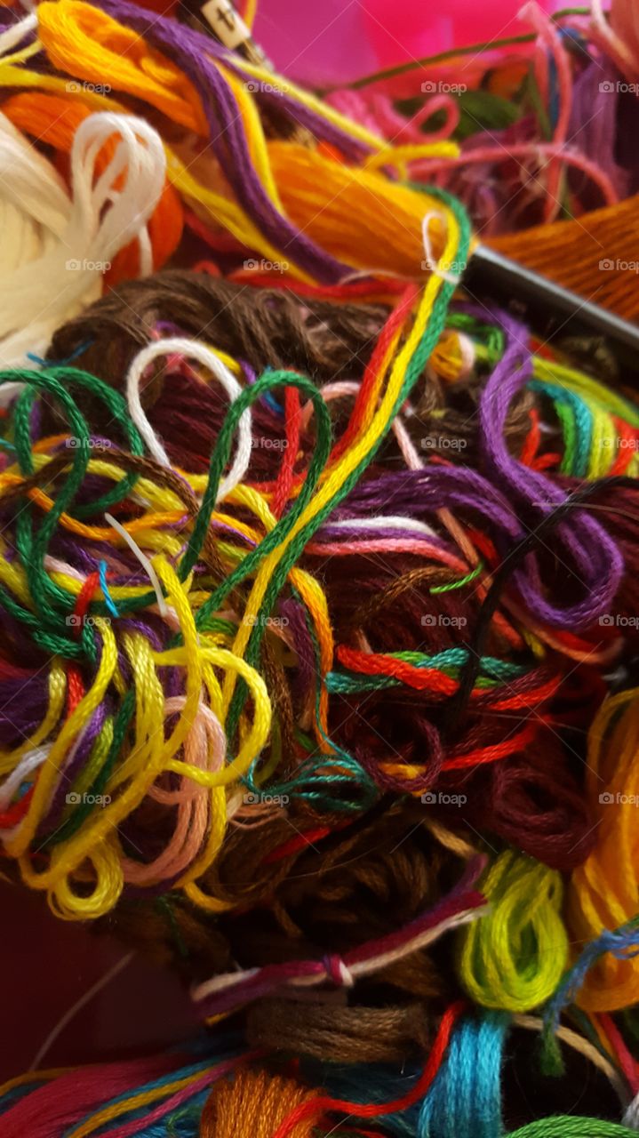 a pile of multicolored strings used to make necklaces and bracelets for girls