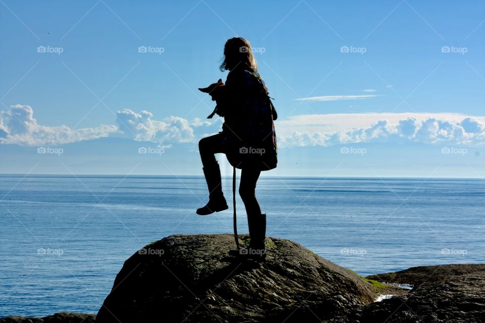 Girl walking her dog on rocky hill against magical backdrop 