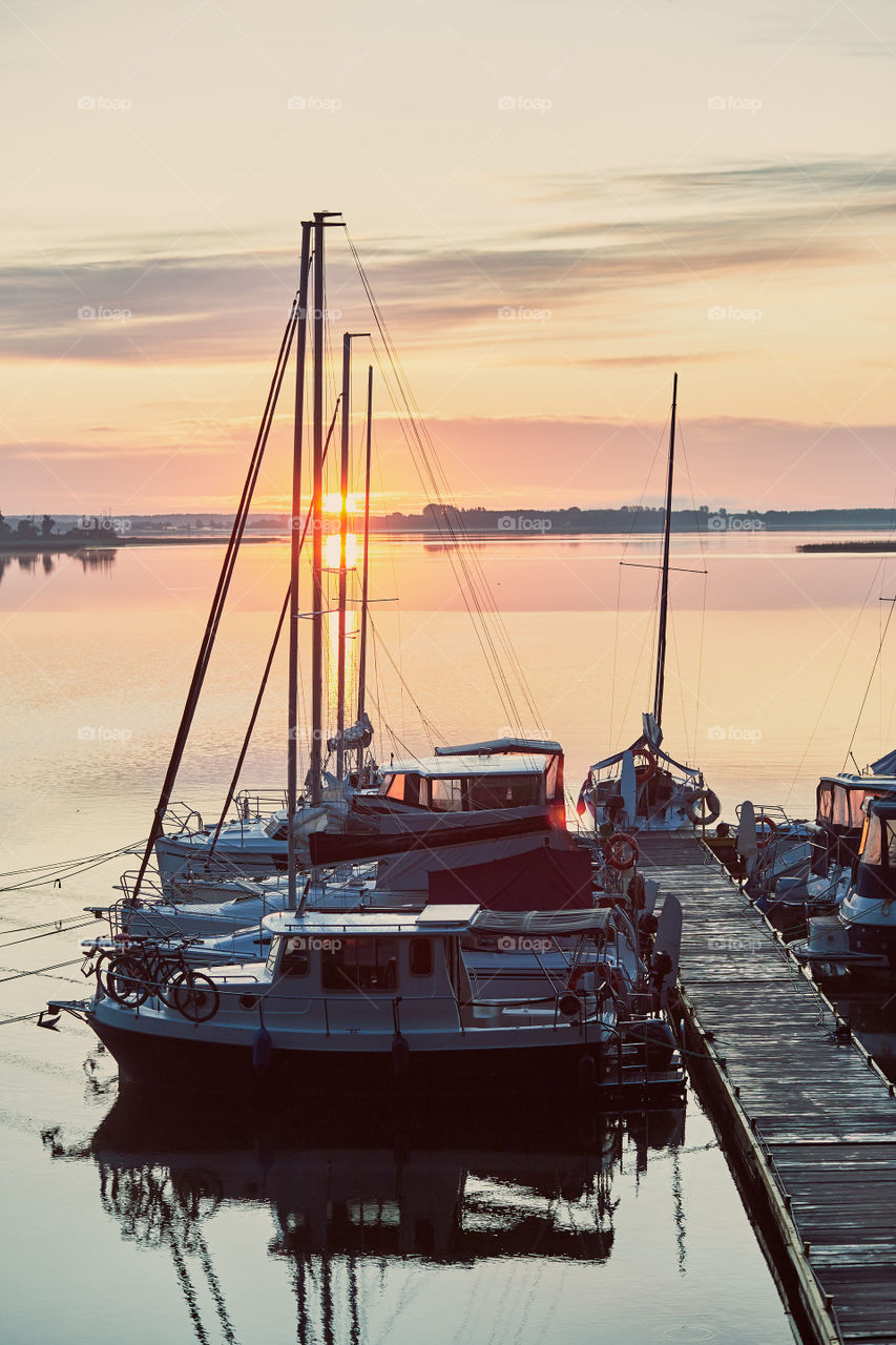 Yachts and boats moored in a harbour at sunrise. Candid people, real moments, authentic situations