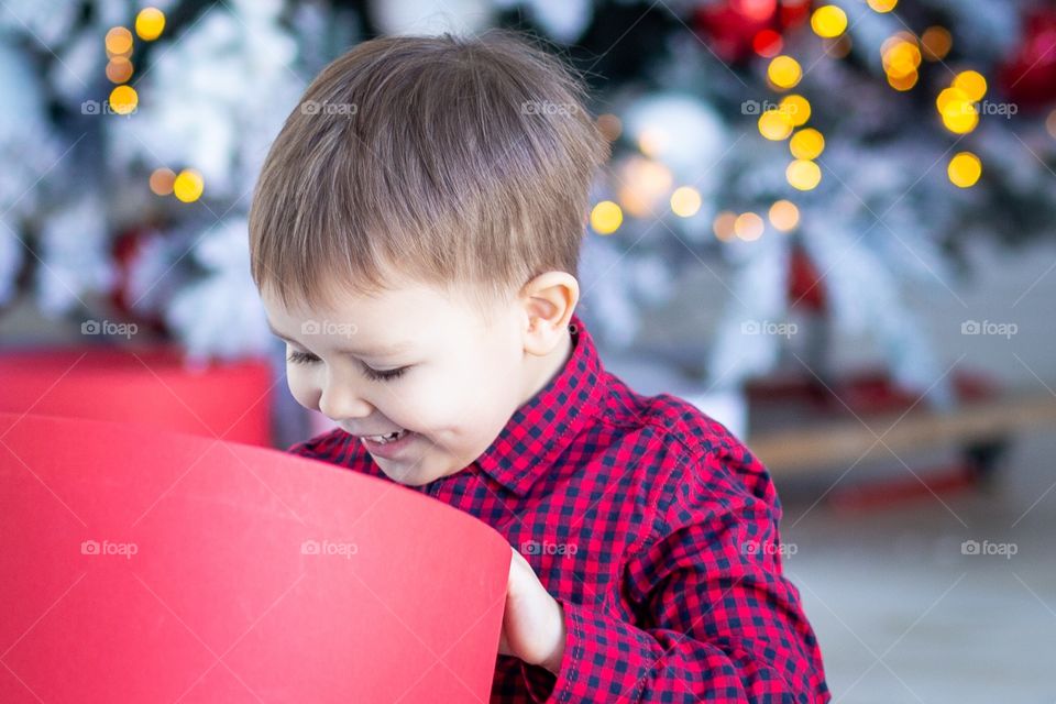 boy and gift box next to christmas tree