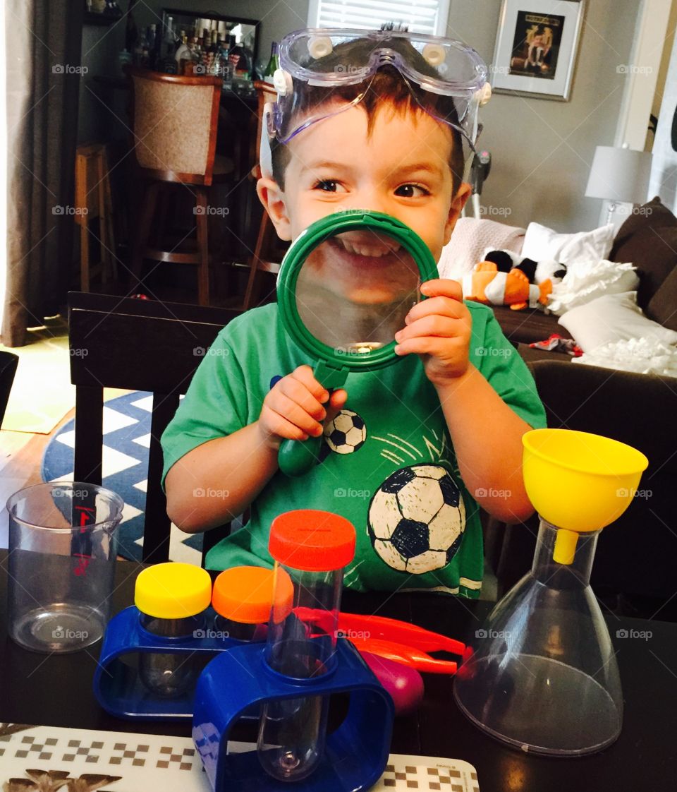 Little funny scientist. 3 year old godson playing with his new science kit