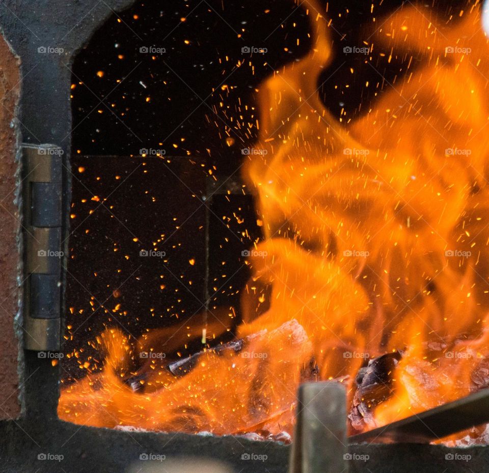 Flames as blacksmith forges metal