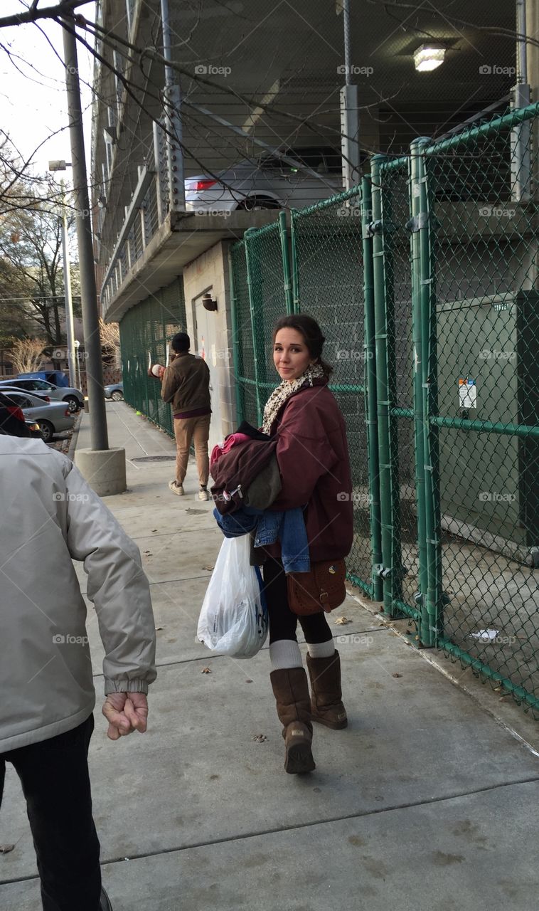 Young woman walking on sidewalk in city