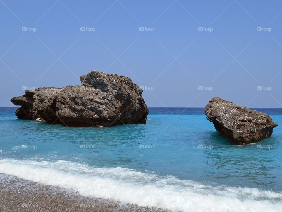 Rock formation in sea against clear sky