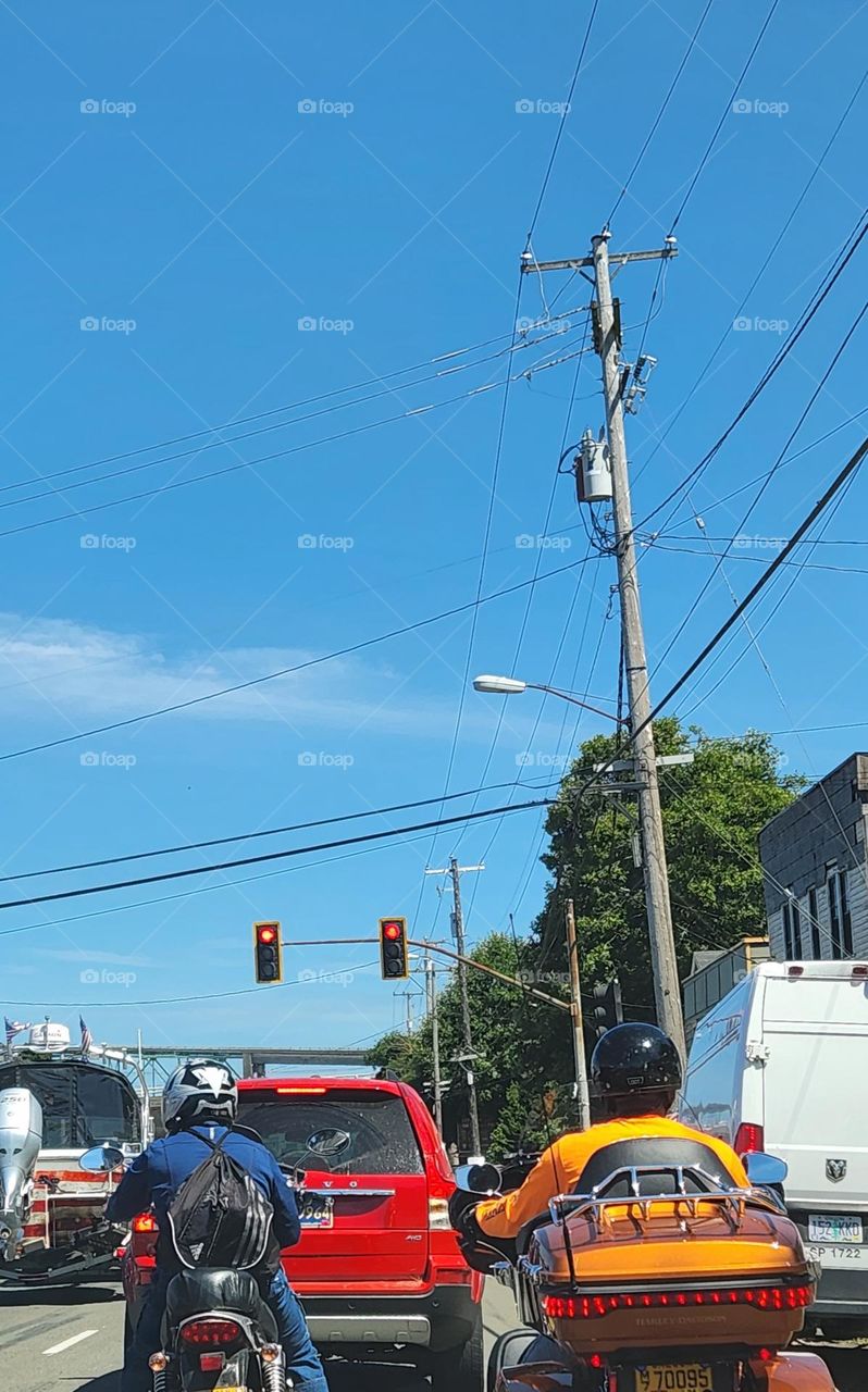 two people wearing helmets and travel gear riding motorcycles through Astoria Oregon traffic