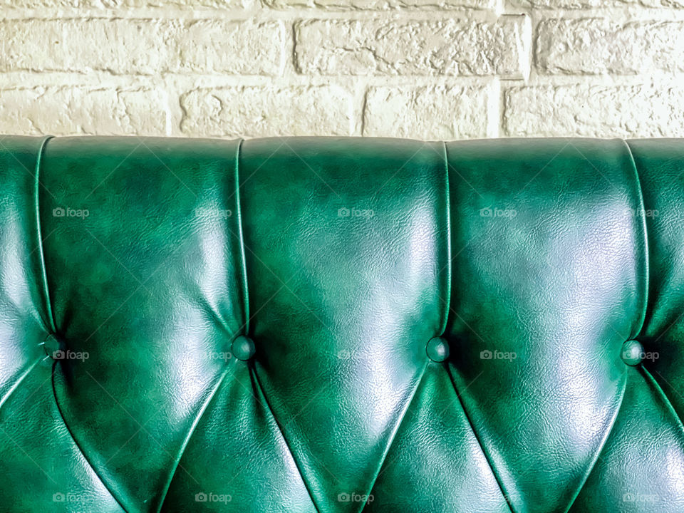 Green leather booth with brick wall