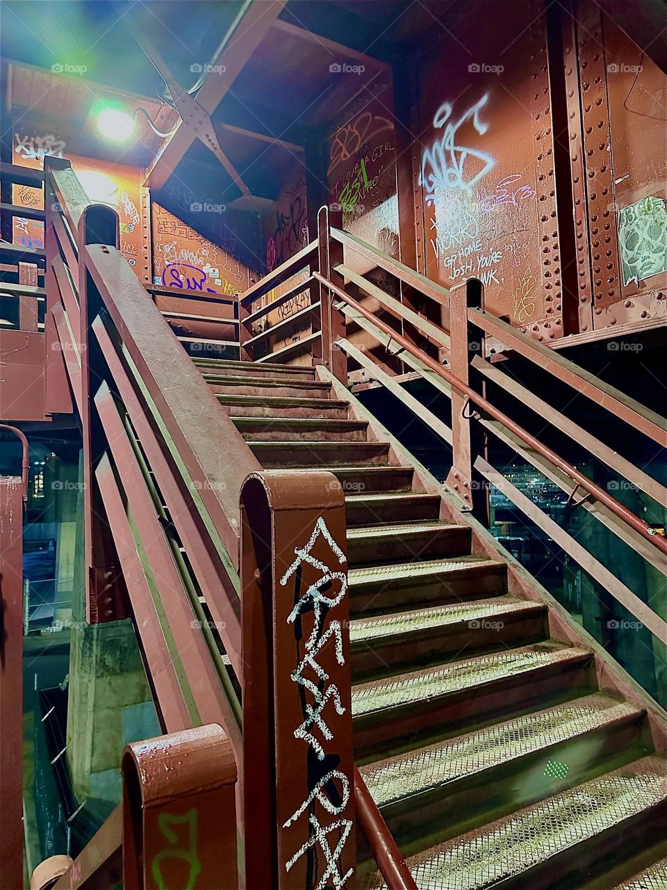The red metal staircase of the „Pulaski Bridge“ at „Newtown Creek“ is illuminated by spotlights at night. This photo shows the „Greenpoint“, Brooklyn side of the bridge. 2023. Hypnotic Productions