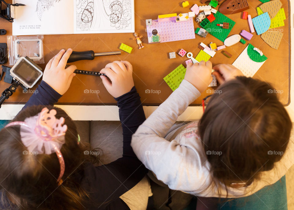 Shot from above of two little girls building and constructing