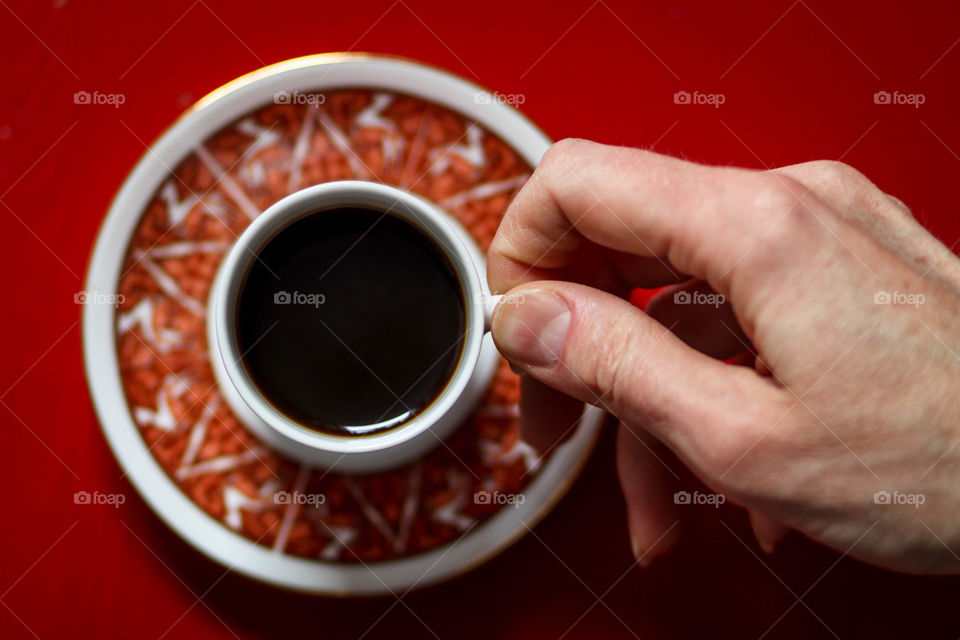 Hand holding cup with black coffee