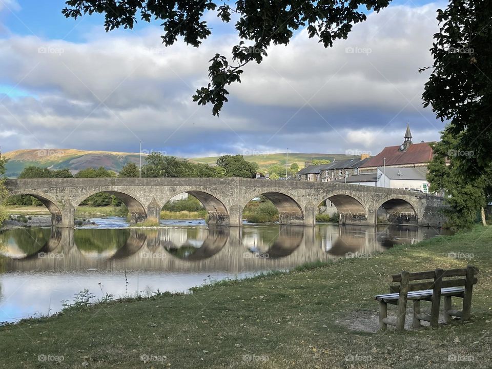 The iconic Wye Bridge spanning gracefully across the River Wye, with its stone archway reflecting softly in the calm waters below. 