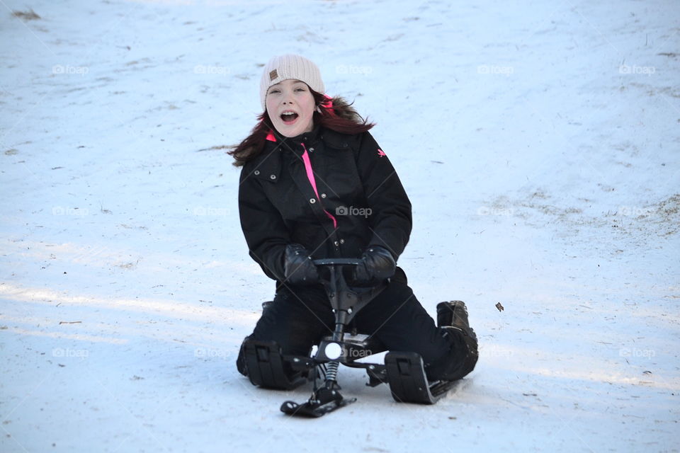 Girl going down the hill in her sled