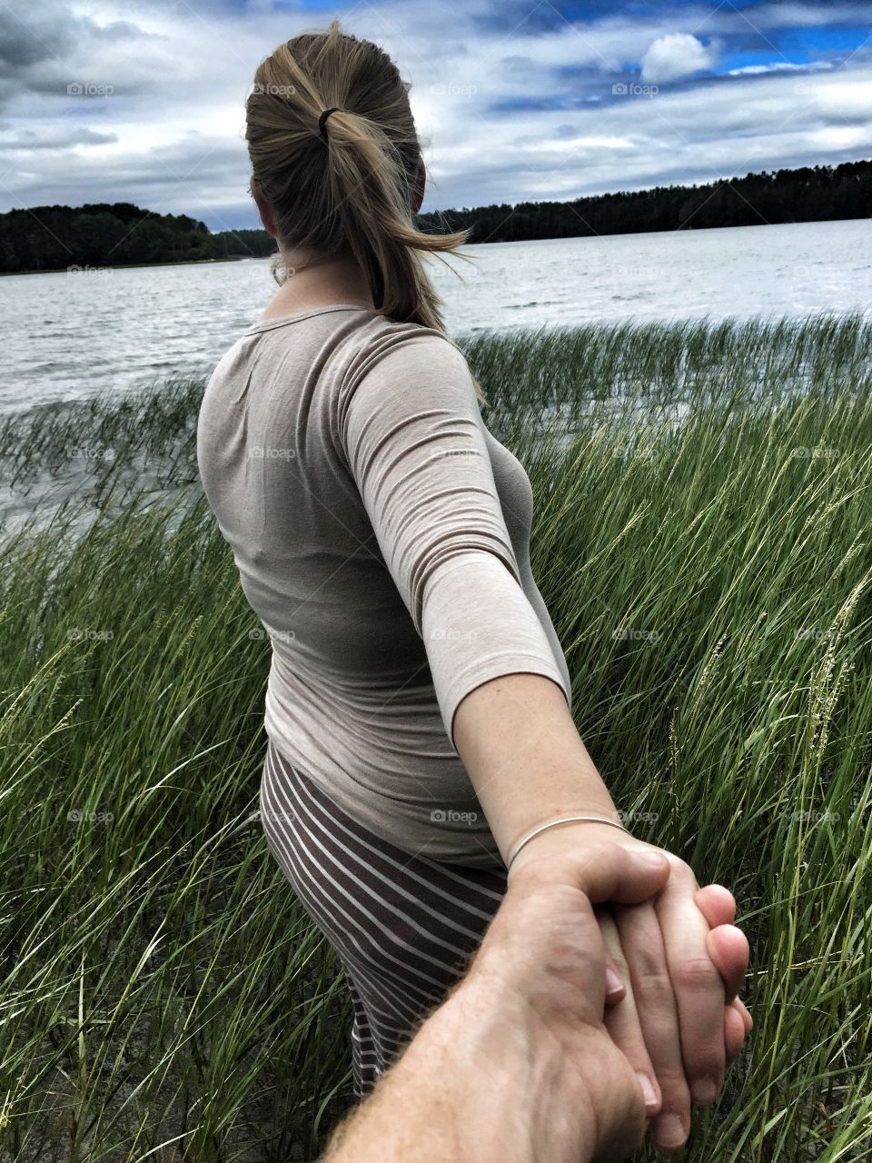 Young pregnant woman walking in Maine ocean 