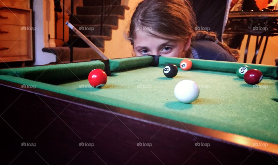 Eyes on the prize. Intense Eyes of a young girl Focus on the mini pool table