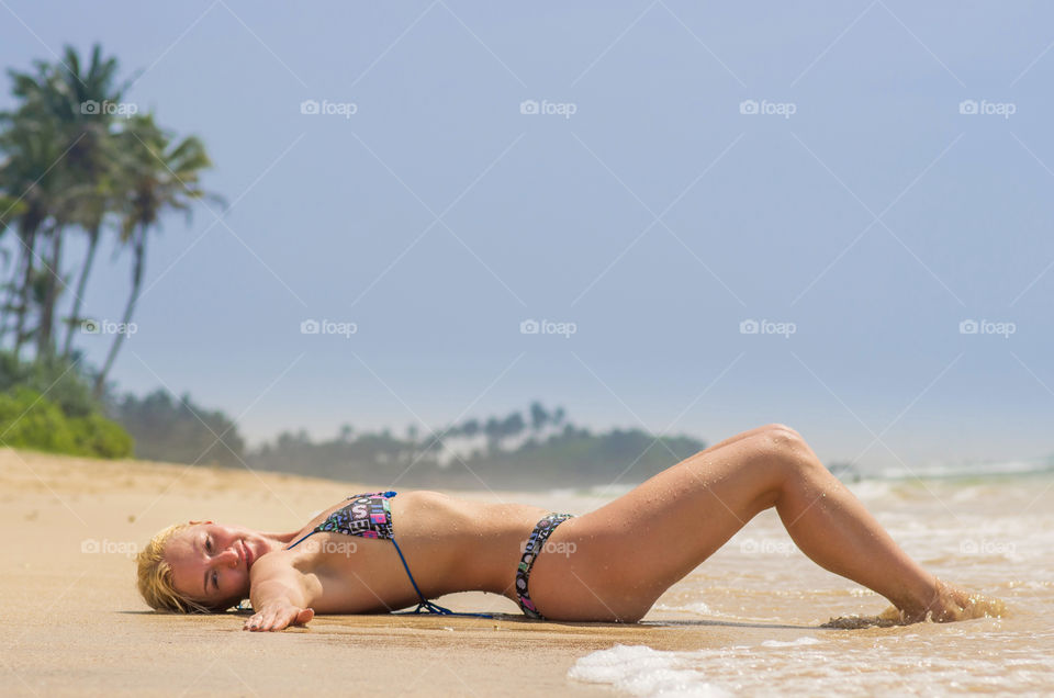 Sexy young woman in bikini lying at beach