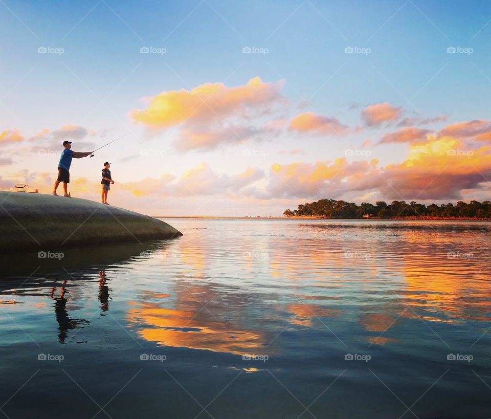 Father and son fishing at sunset 