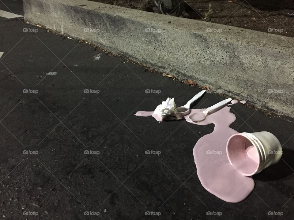 Spilled ice cream lays abandoned in a parking lot. 