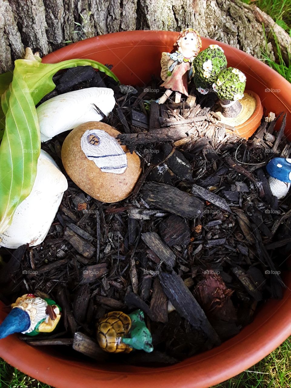 Figurines and dying leaf in a pot