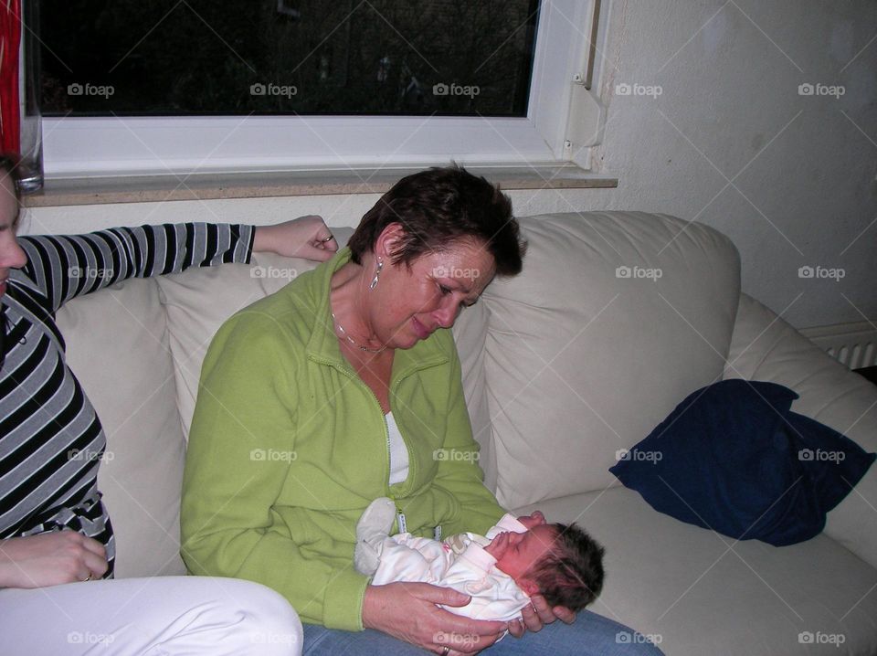 Proud grandma. Grandma has her newborn granddaughter on der lap for the first time. Look how she admires her granddaughter. Tears of pride and Happiness.