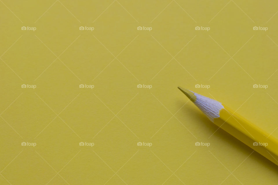 Yellow pencil on yellow paper background