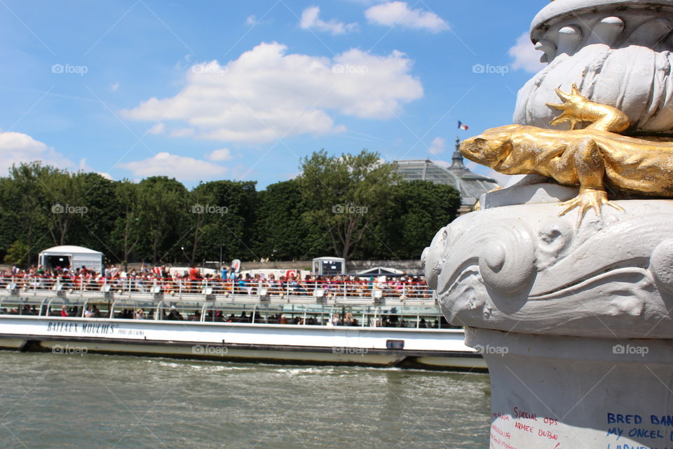 a statue of lizard is watching the tourists in a boat in Paris