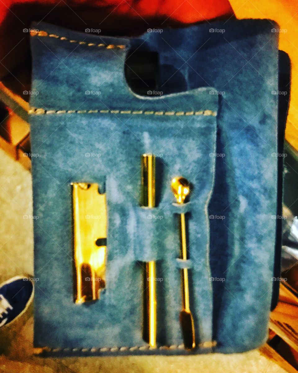 Gold plated drug paraphernalia. A gold spoon, razor, and straw in a blue suede wallet used for doing cocaine. 