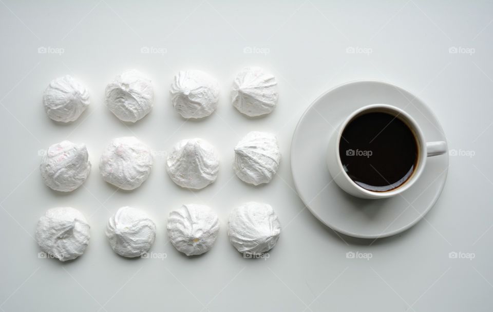 coffee mug and sweet sugar meringues on a white background top view