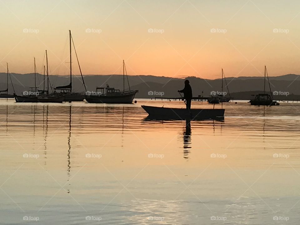 Man rowing boat under a fiery sunset