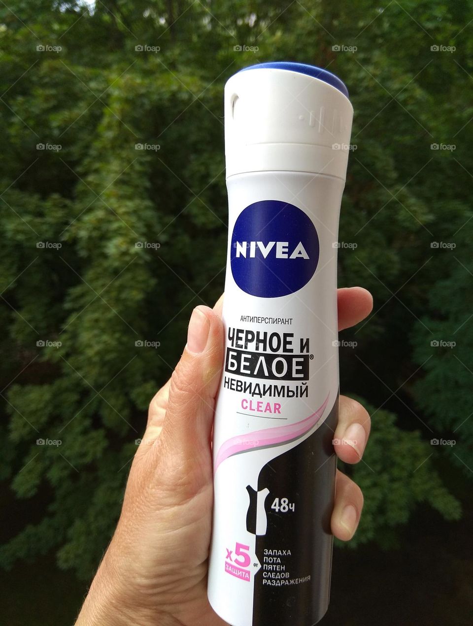 Nivea deodorant spray in the female hand green summer background, love products