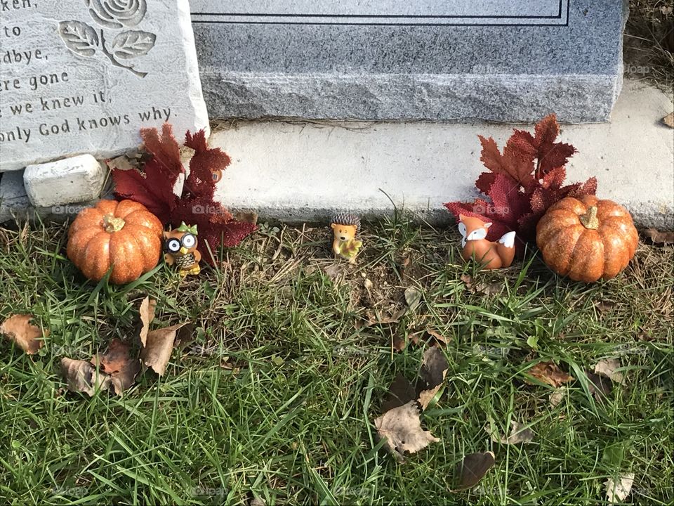 Cute little figurines and pumpkins in front of a tombstone .