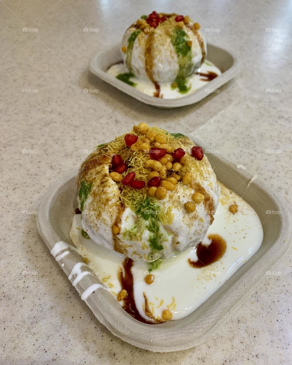Raj kachori- an Indian snack served with cold curd and cold green chutney as well as cold tamarind chutney. It has filling of sprouts, boiled and cut potatoes, black chana(chickpea). On the top decorated with sev , boondi and pomegranate seeds.