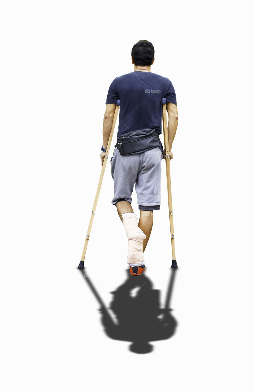Isolated Asian man used wooden crutches walks on a white background with clipping path.