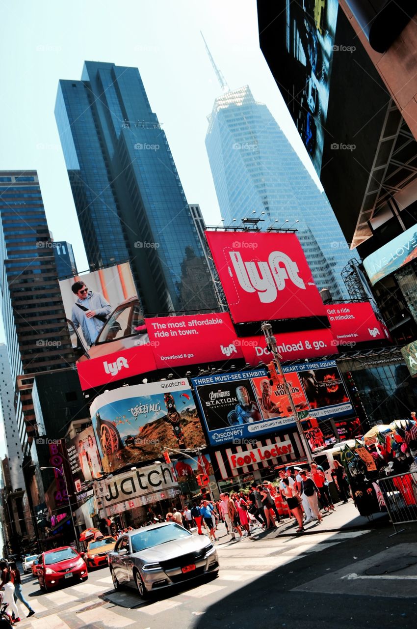 The City. A view of a busy Manhattan street. A huge sign of Lift competes with the ones from Watch, Discovery and Foot Locker. 