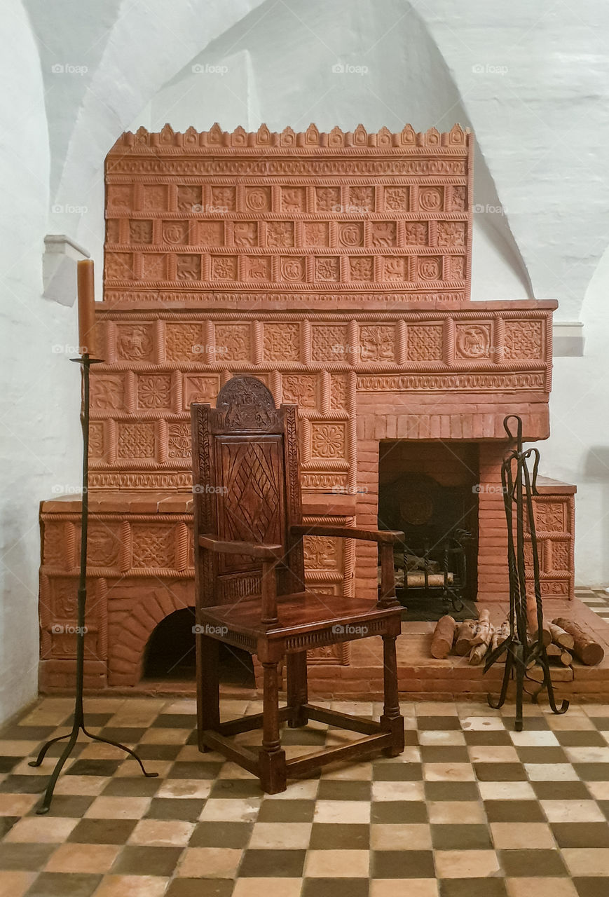 Moscow, English Chambers, authentic historical medieval interior with vaulted ceiling with a massive wooden ornamental chair, candles and a fireplace with tiles