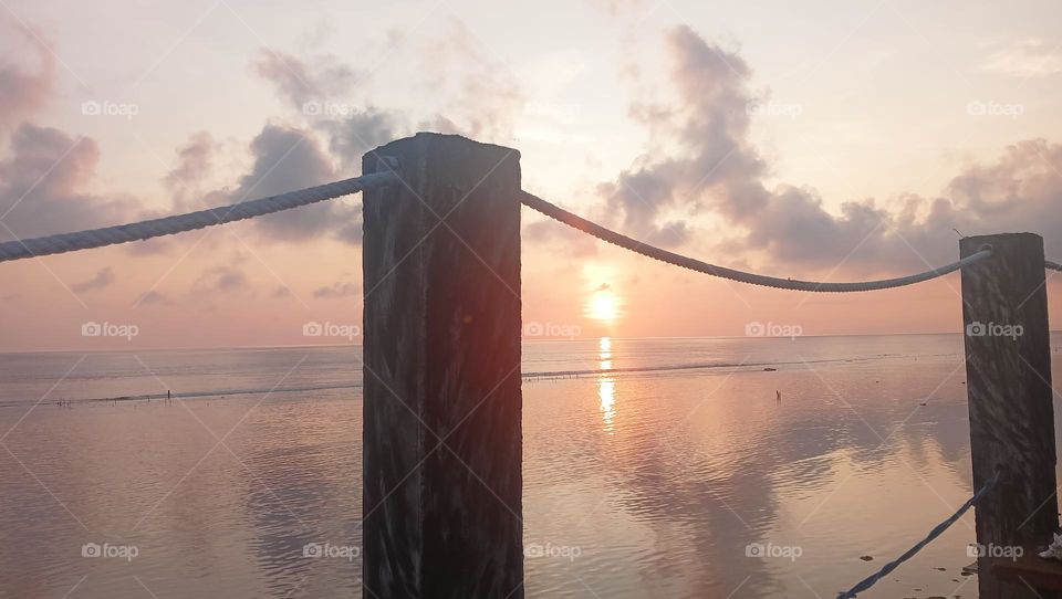 sunrise behind rope fence