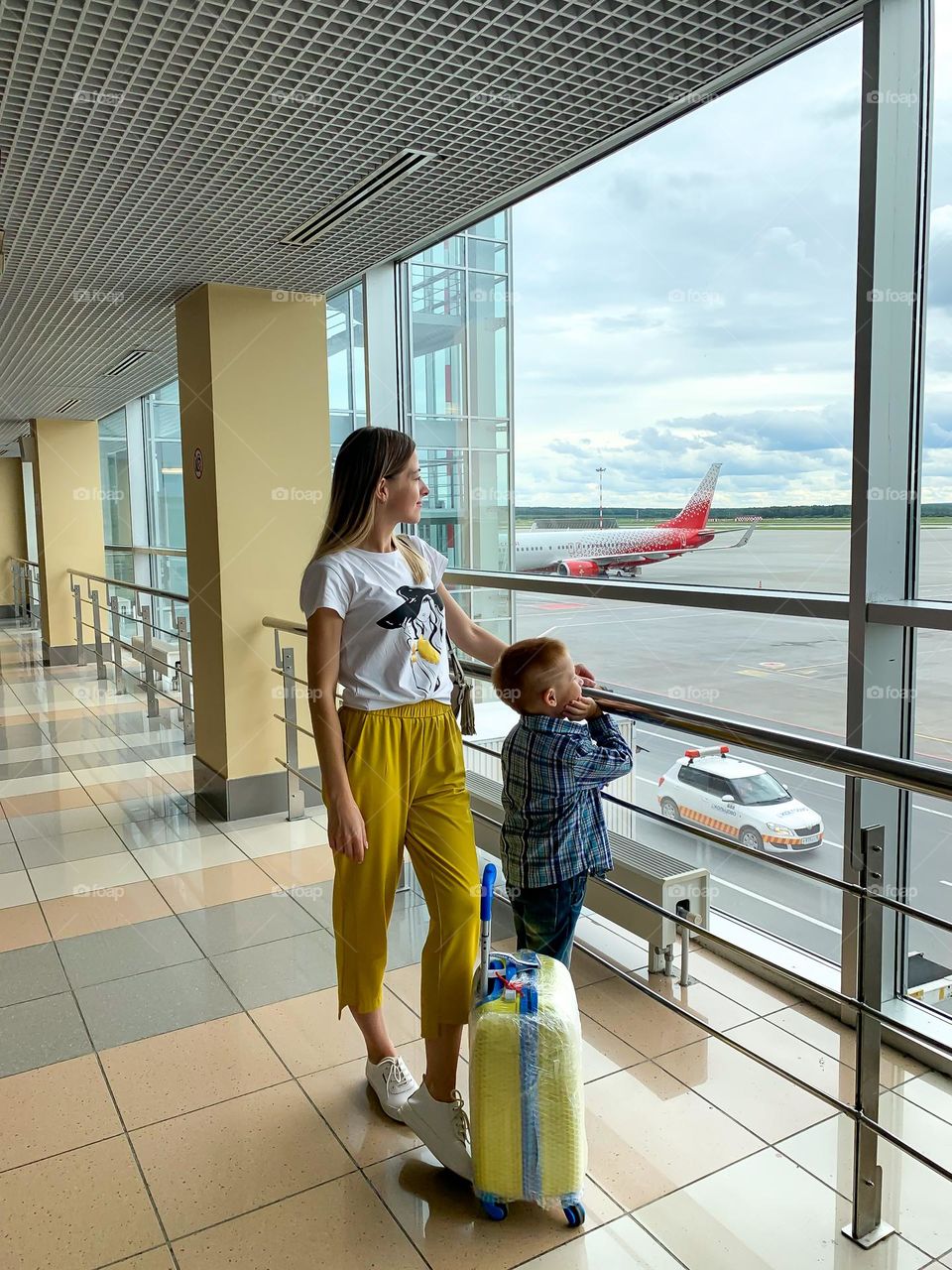 Mom and son looking at the window in the airport 