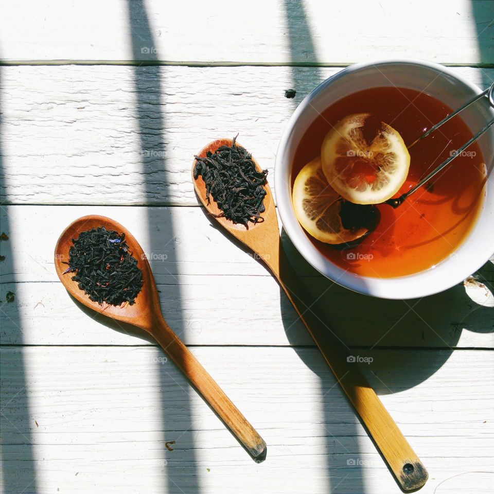 A cup of black tea and tea in spoons