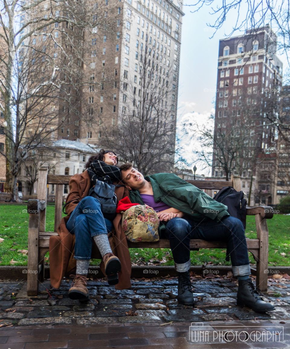 Lovers laugh at the world on a bench in their own world 